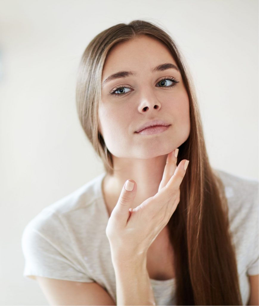 Teenage girl checking for acne scars in the mirror