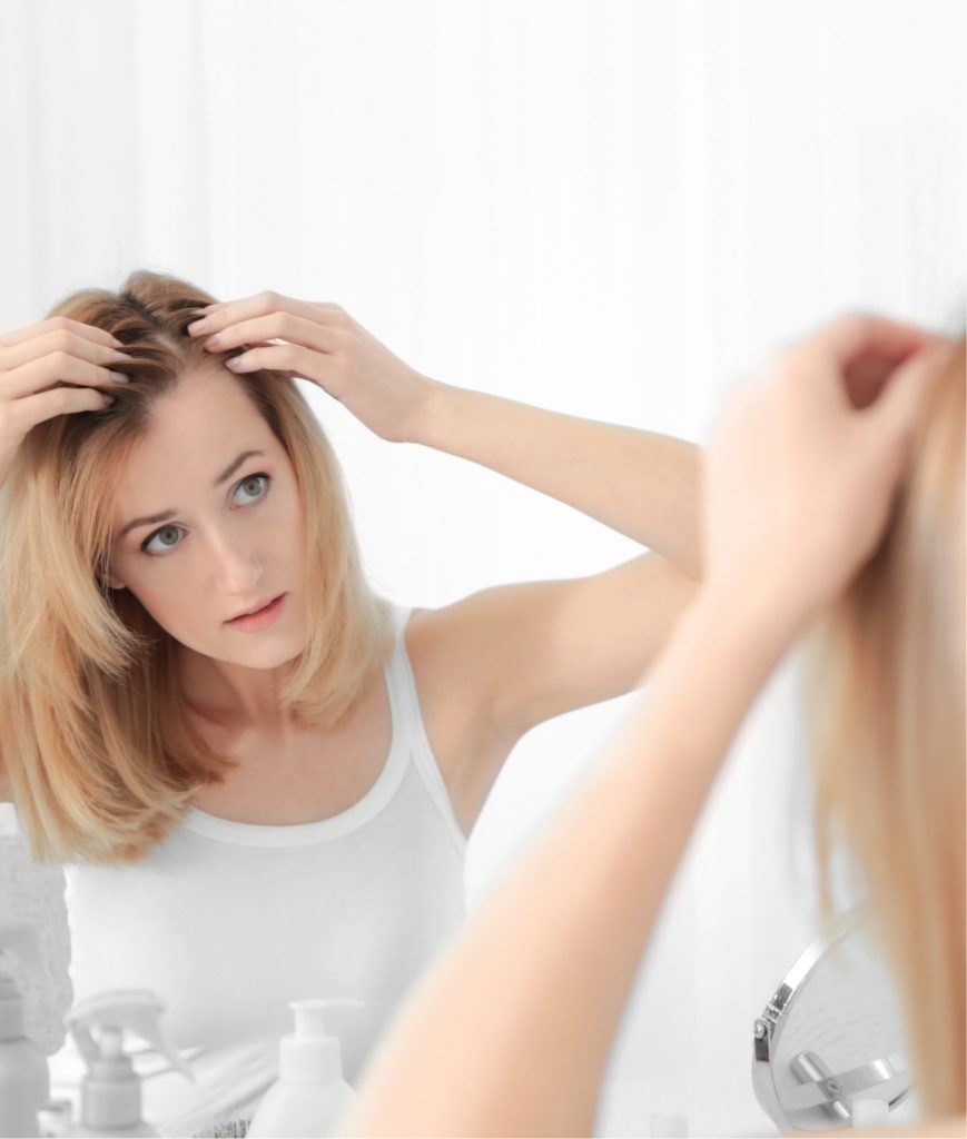 Woman checking for hair loss in the mirror